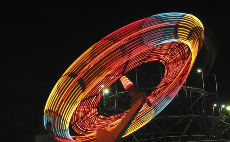 multicoloured-neon-spinning-fairground-ride-on-black-background