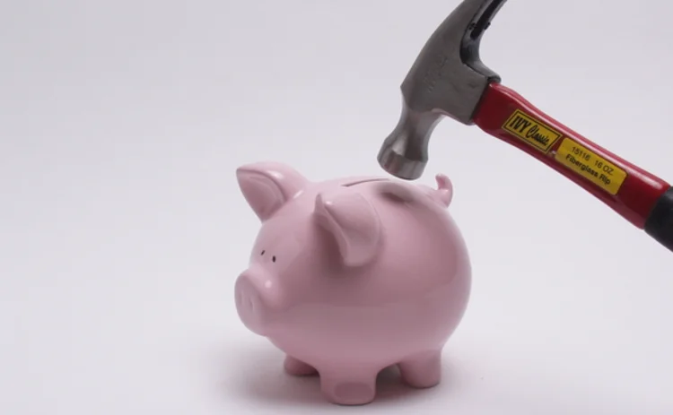 A hammer about to smash a piggy bank