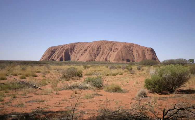 Uluru in the Australian outback against a blue sky