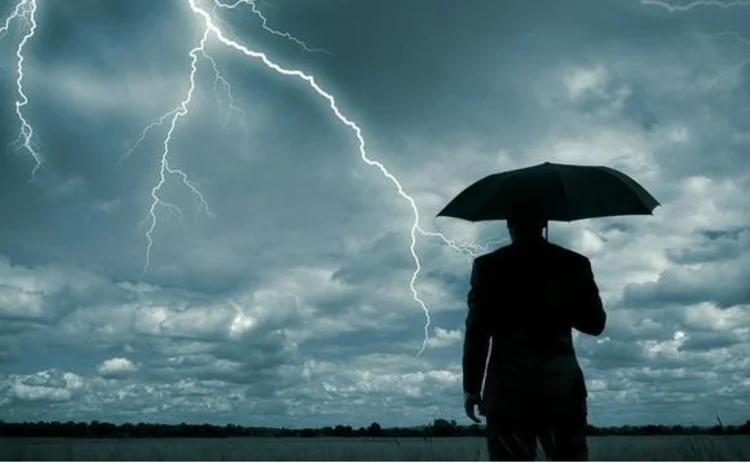 Man with umbrella under stormy skies
