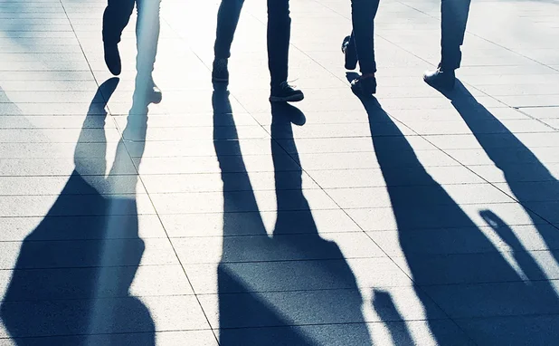 Long shadows of people standing on a pavement