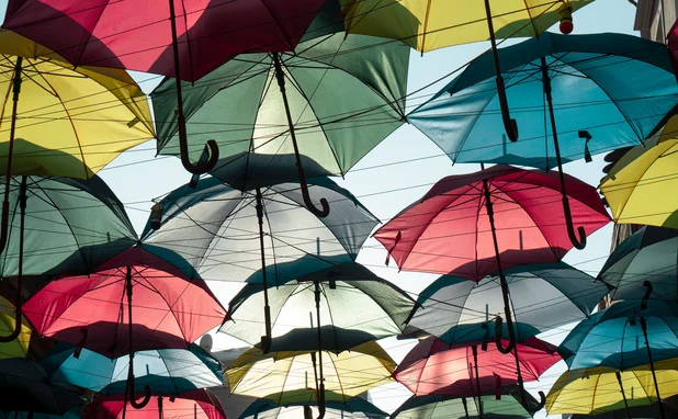 Multiple coloured umbrellas suspended in a sunny sky