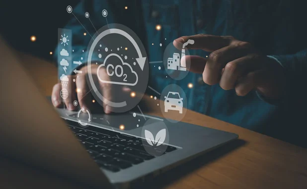 a hand points to climate change icons that have come from a laptop screen