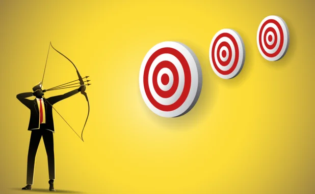 A man holding a bow and arrow with three arrows aims at three targets, one of which is larger than the others