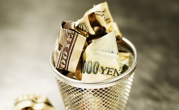 Yen and dollars in wastepaper basket