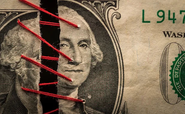 Two pieces of dollar banknote being stitched together