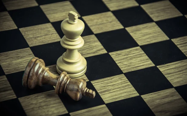 A chess board, with one standing white king and one fallen black king