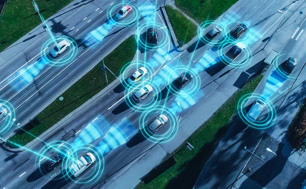 Aerial view of cars self-driving using AI, with computer representation of sensors emanating from the cars