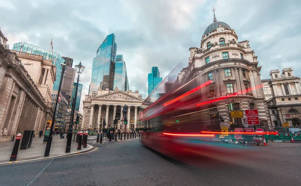 Motion blurred red bus heading towards Bank of England 