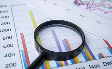 A magnifying glass hovers over financial data