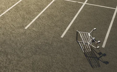 A shopping cart lies on its side in an empty car park