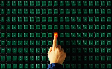 A finger switches on a button, which lights up red, on a panel full of green buttons that are switched off