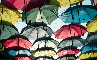 Multiple coloured umbrellas suspended in a sunny sky