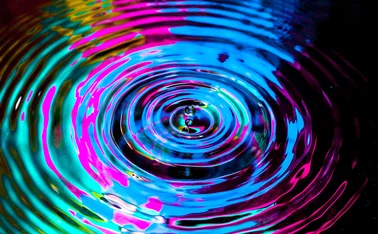 A droplet creates a ripple effect in multi-colours