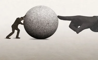 A man pushes a large concrete ball, while a hand on the other side tries to stop it moving