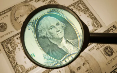 a dollar bill has a magnifying glass hovering over it to denote analysis