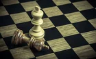 A chess board, with one standing white king and one fallen black king