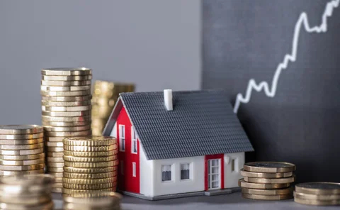 Model house surrounded by coins