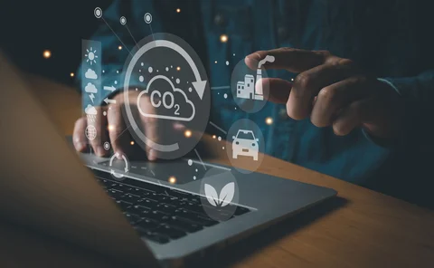 A hand points to climate change icons that have come from a laptop screen