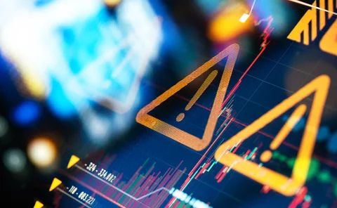 Warning signs over background of erratic chart data on a screen