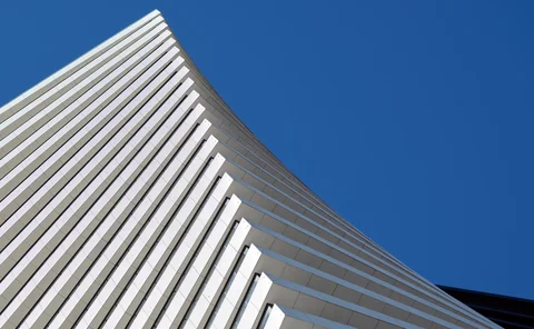 The tip of a white, geometric building against a blue, sky background