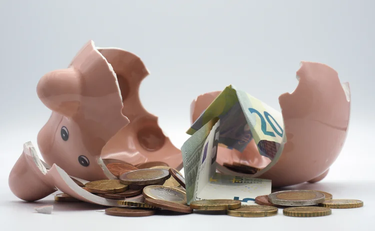 A smashed piggy bank with cash around it