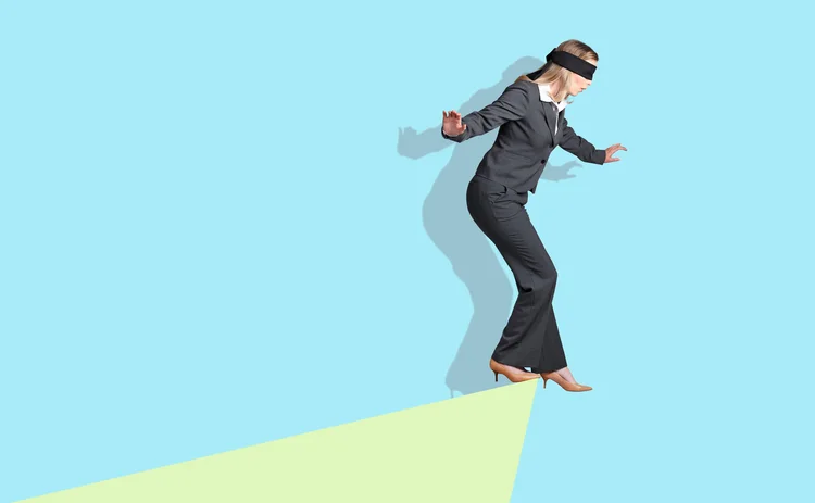 A businesswoman with a blindfold on is teetering at the edge of an abstract drop