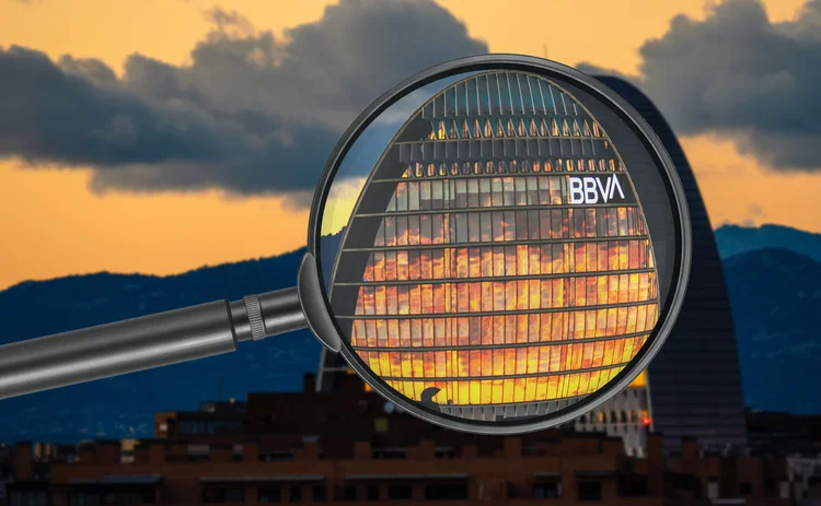 Magnifying glass highlights BBVA’s Madrid building with a cloudy, sunset background
