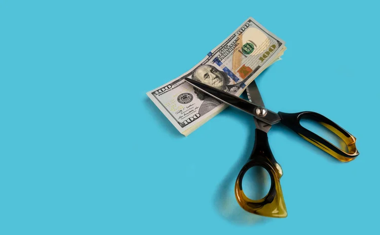 Scissors are about to cut into some dollar banknotes