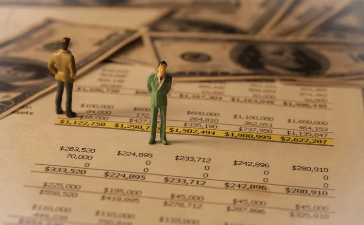 Tiny models of businessmen stand on some sheets of financial plan pages