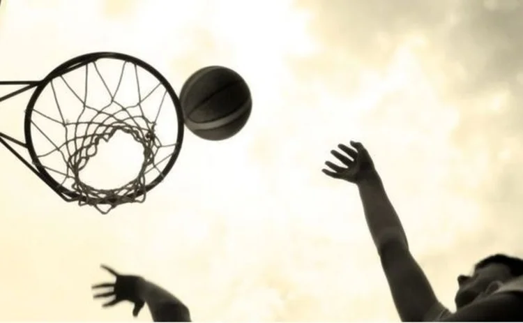 Two basketball players jumping up to the net