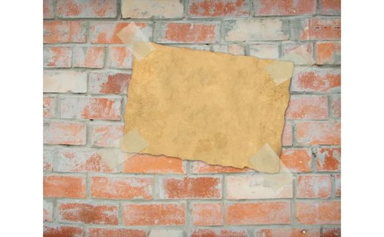 old-piece-of-paper-taped-onto-brick-wall