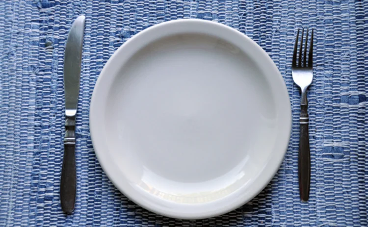 An empty plate flanked by a knife and fork