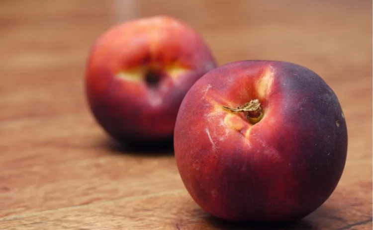 A close-up of two peaches on a table