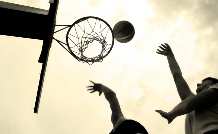 Two basketball players jumping up to the net