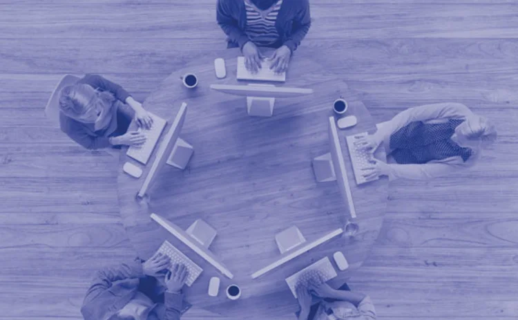 People working round a table on computers portraying a shared future