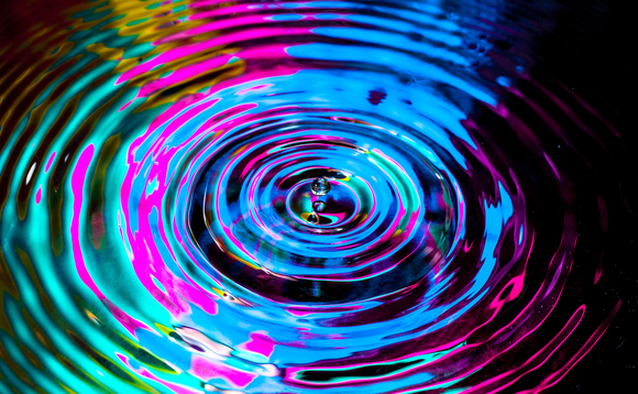 A droplet creates a ripple effect in multi-colours