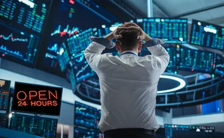 A trader looking tired on a trading floor where a sign reads ‘open 24 hours’
