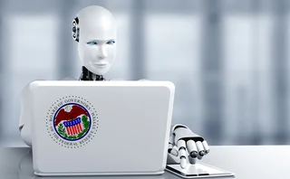 A robot sits at a laptop, which has a Federal Reserve Board sticker on it