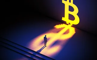 Man standing in front of giant glowing bitcoin symbol casting a dollar shadow 