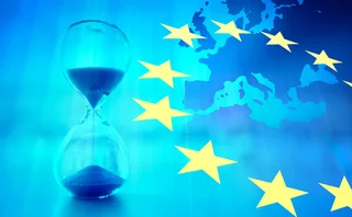 An hourglass is superimposed over an image of Europe with the EU flag