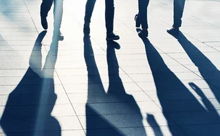 Long shadows of people standing on a pavement