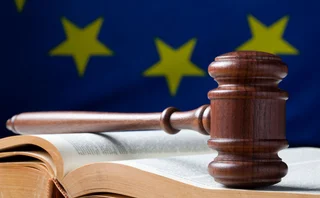 a judge’s gavel with a european flag behind it