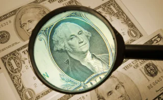 a dollar bill has a magnifying glass hovering over it to denote analysis