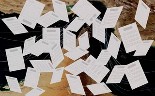 Exam papers fly randomly in front of a backdrop of the strait of hormuz