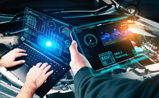 Two mechanics examining a car’s computer diagnostics on laptop and tablet