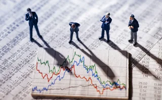 Small plastic figurines of businesspeople look quizzically at a large financial chart