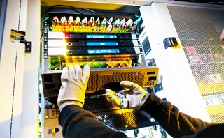 Gloved engineer fixes computer hard drive in server stack