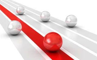 3D illustration of a red sphere leading four silver spheres along parallel tracks, symbolising competition and leadership