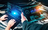 Two mechanics examining a car’s computer diagnostics on laptop and tablet